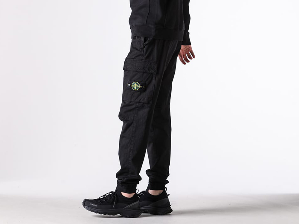 Close-up view of the cargo pocket and logo patch on the STONE ISLAND pants