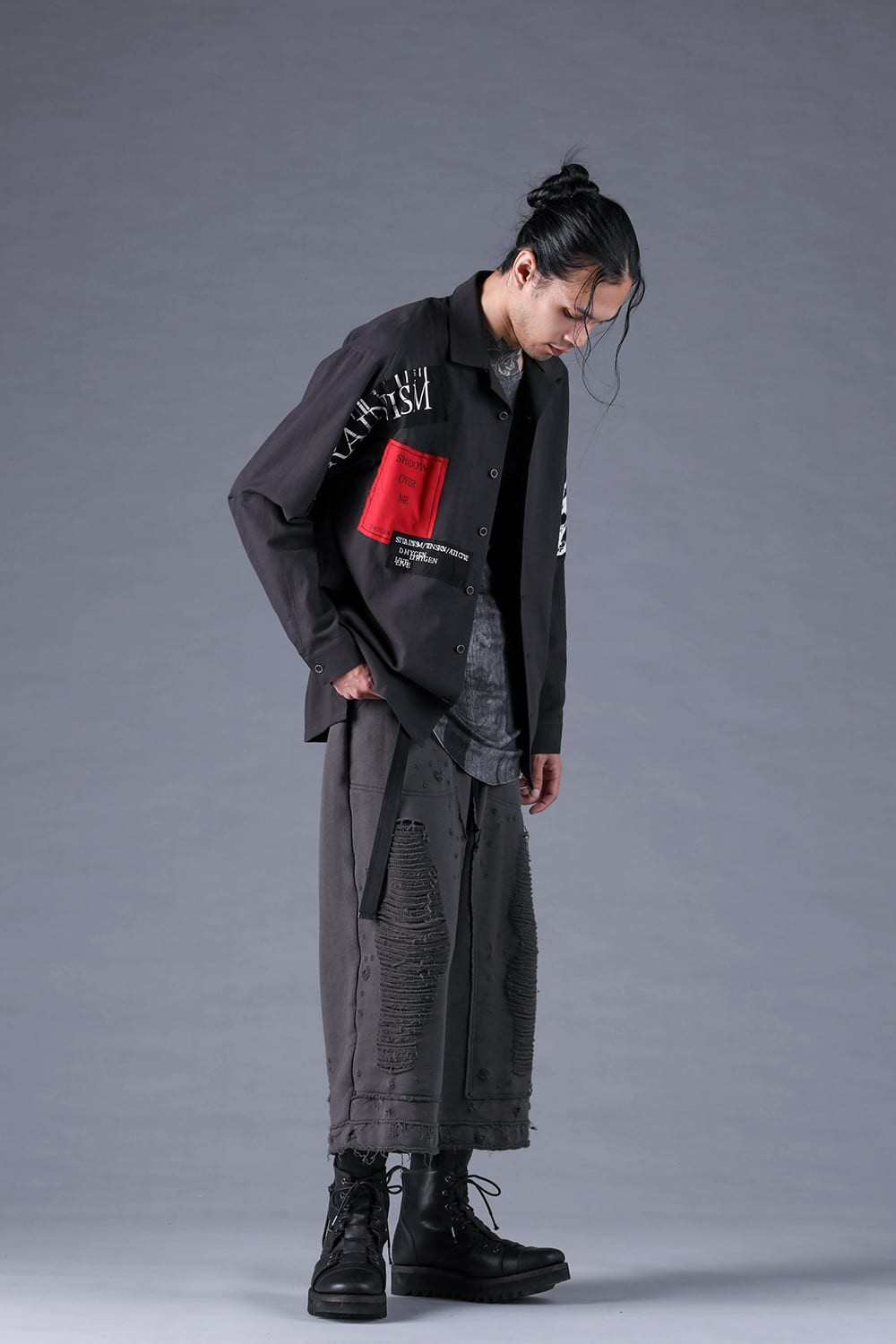 赤いグラフィックのある黒のトップスとグレー系パンツのルック