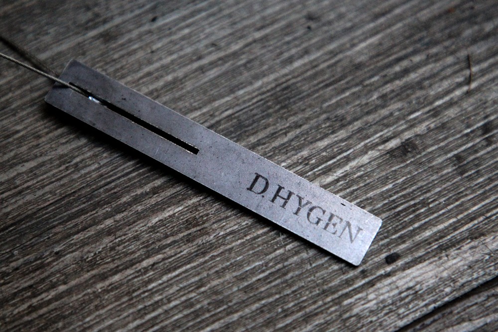 D.HYGENのブランド名が刻まれた金属製タグ
